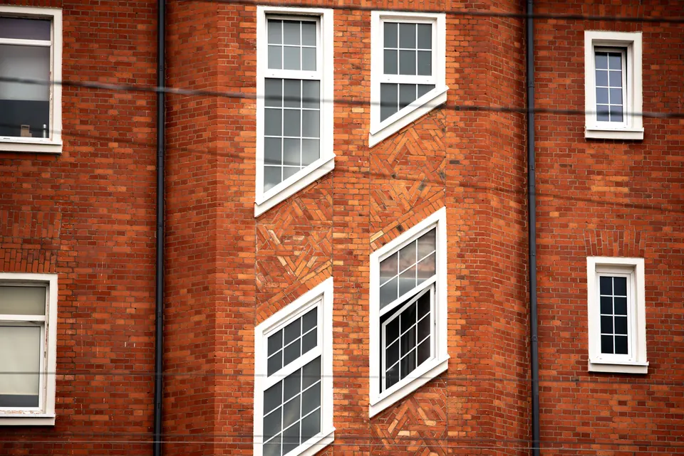 Klinkerfassade eines Wohnhauses mit weißen Sprossenfenstern und Zierverband